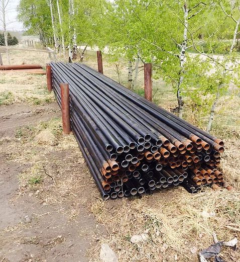 Picture of stacked metal pipes laying on the ground