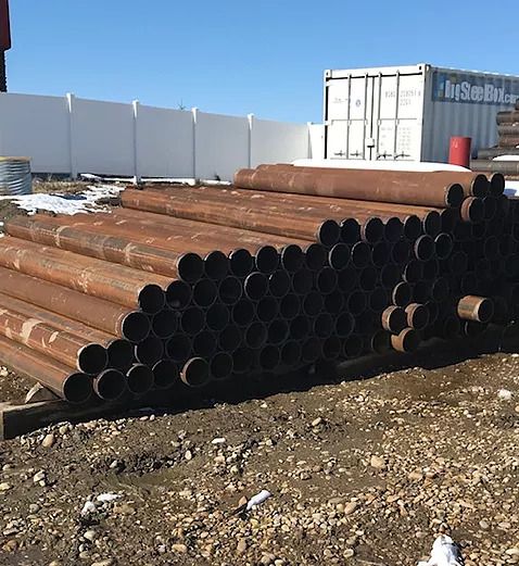 Image of stacked metal pipes laying on the ground